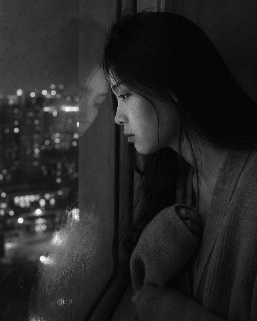 Retrato melancólico junto a la ventana de un apartamento por la noche