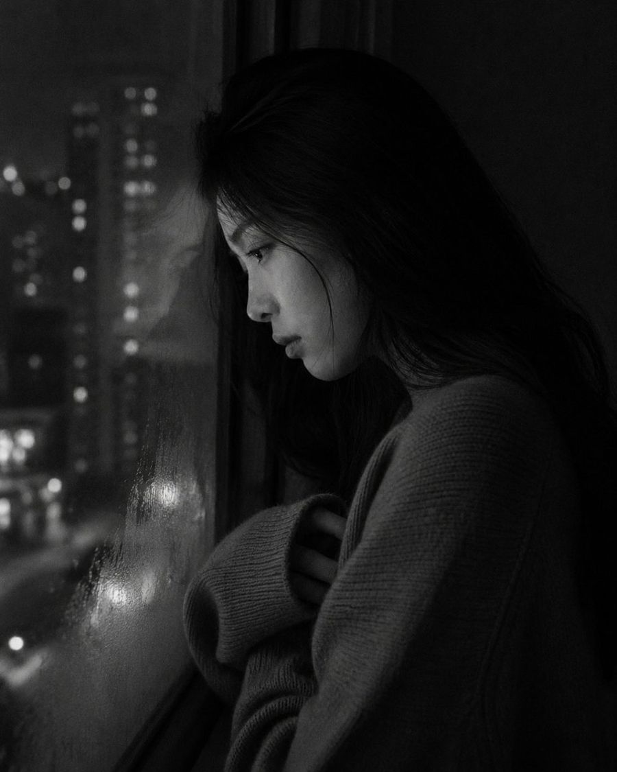 Retrato melancólico junto a la ventana de un apartamento por la noche