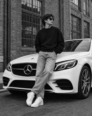 倚靠白色 Mercedes-Benz 的男子